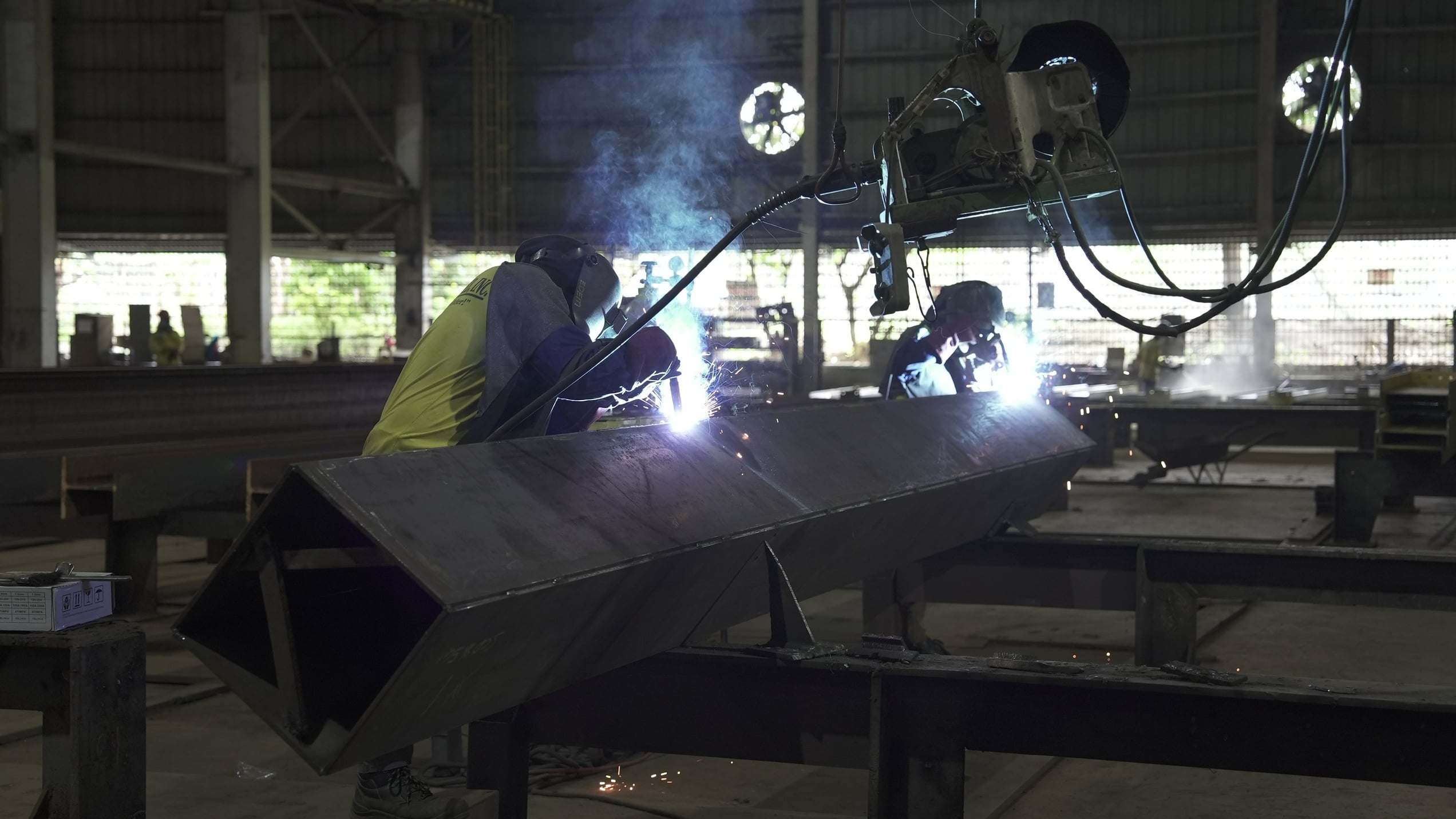 Steel fabricators welding a structural steel assembly in the shop